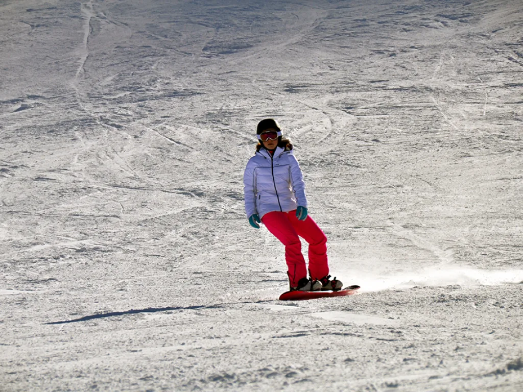 Snowboarderin in heller Jacke auf der Piste.